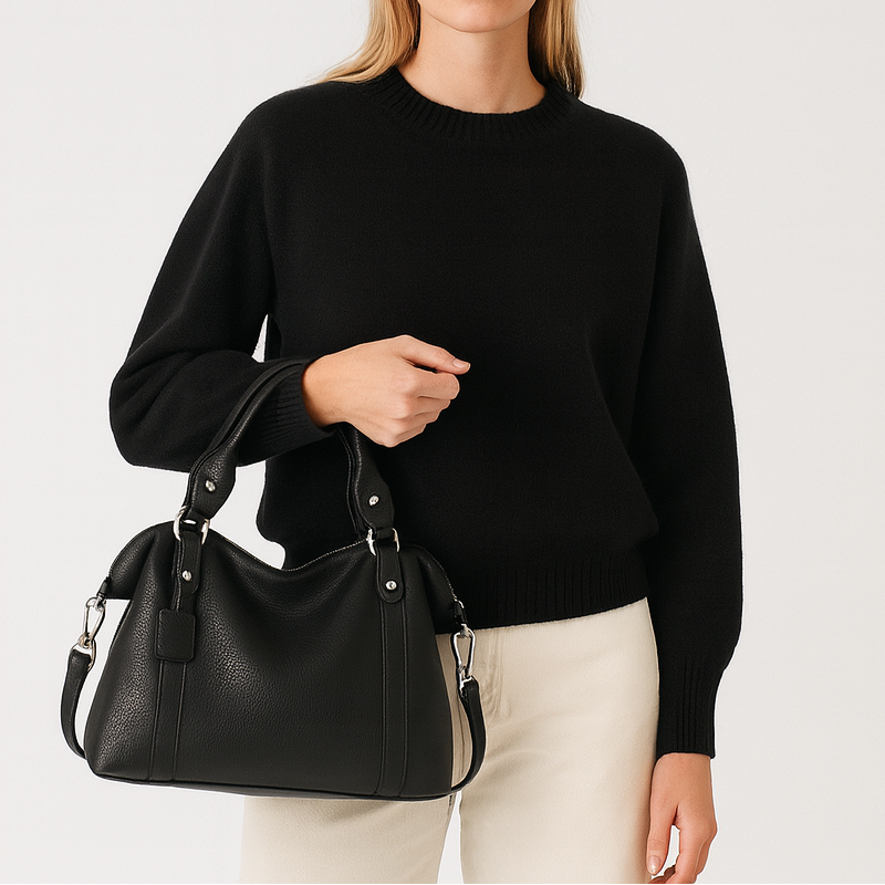 Medium structured handbag with dual handles and side strap details.