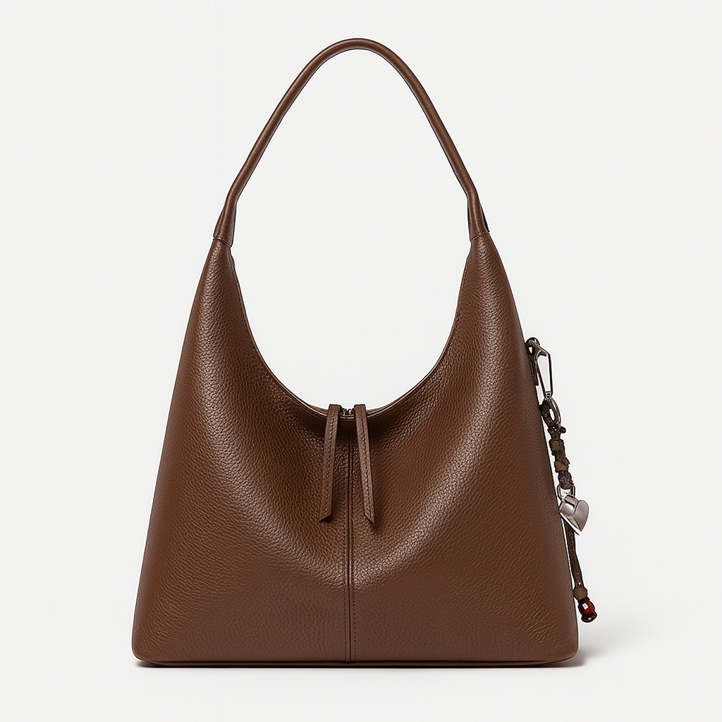 Minimalist slouchy shoulder bag with a single wide strap and decorative charm.