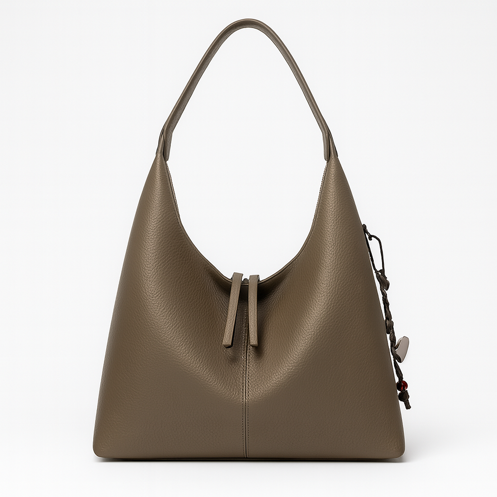 Minimalist slouchy shoulder bag with a single wide strap and decorative charm.