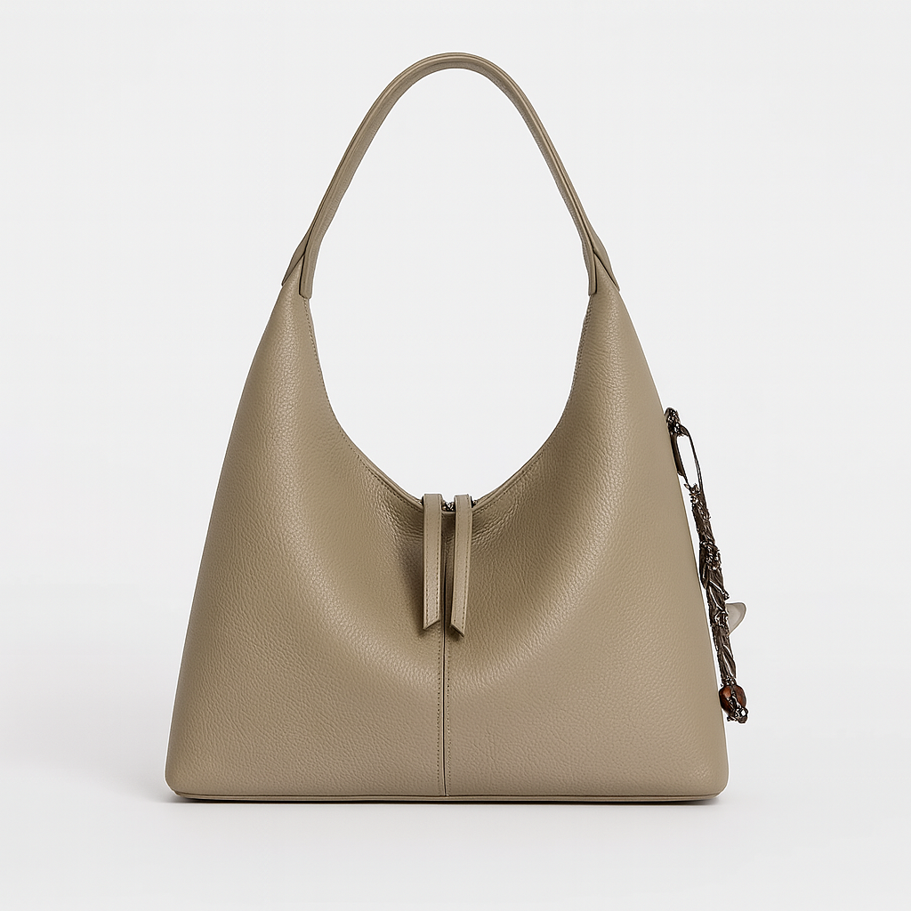 Minimalist slouchy shoulder bag with a single wide strap and decorative charm.
